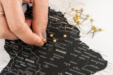 Pins werden in eine Breuers Weltkarte gesteckt, um Orte und Reiseziele zu markieren